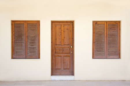 yellow wall with retro door and two windowsの写真素材