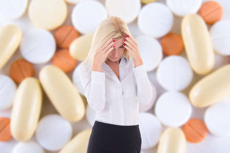young business woman with headache over background with pillsの写真素材