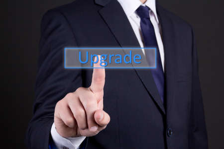 businessman hand pressing upgrade button over dark backgroundの写真素材