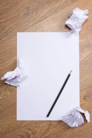 pencil on clear white paper with crumble paper balls on wooden table background