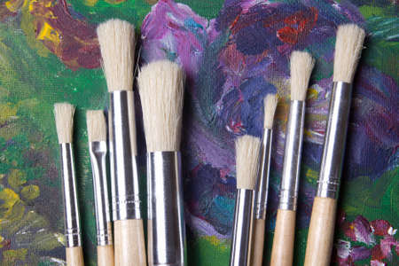 close up of wooden paint brushes set on oil paints