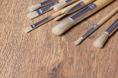 close up of paint brushes set on wooden table