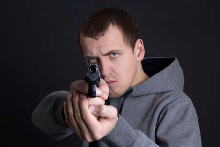 man criminal aiming with gun over grey backgroundの写真素材