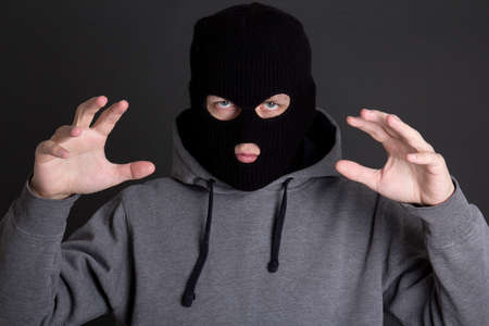 angry man criminal in black mask over grey background