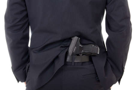 man concealing gun in pants behind his back isolated on white background
