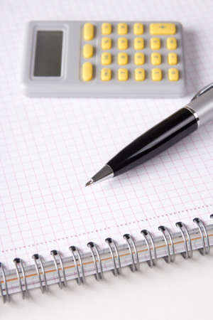 business concept - close up of note book with checked pages, pen and calculatorの写真素材