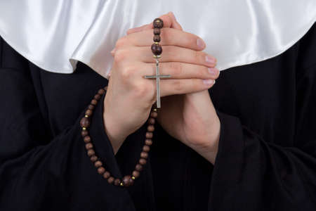 close up of rosary in female nun hands