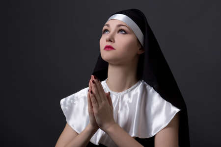 beautiful woman nun with red lips praying over grey backgroundの写真素材