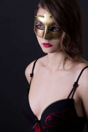 portrait of beautiful woman in lingerie and mask over grey backgroundの写真素材