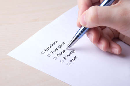 female hand filling customer survey with metal pen