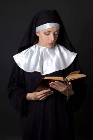 young woman nun reading bible over grey backgroundの写真素材