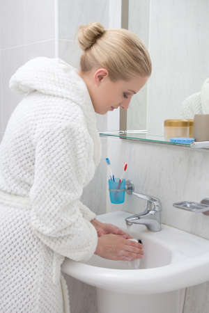 young beautiful woman washing hands in bathroomの写真素材