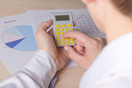 business concept - close up of male hands accounting something with calculator
