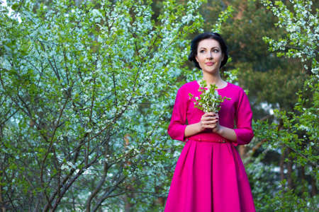 young beautiful dreamy woman walking in spring cherry garden
