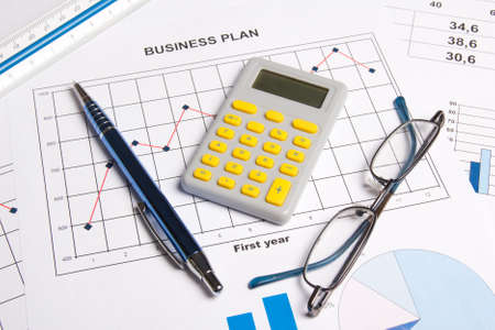 close up of business plan with graphs, charts, glasses, pen and calculator on the tableの写真素材