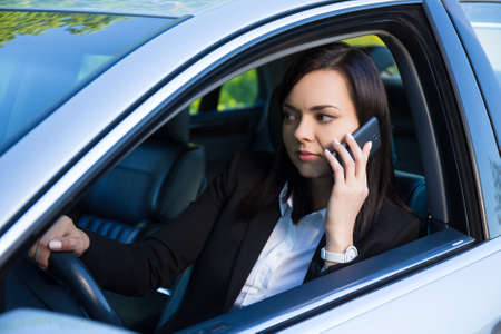 young successful business woman talking on smartphone in her car