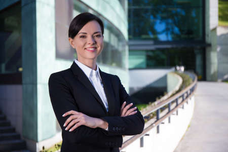 business concept - young beautiful woman in suit over modern city background