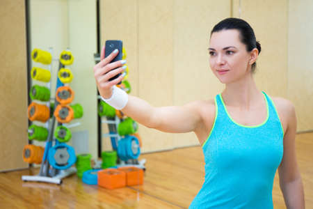 young sporty woman making selfie photo on smartphone in gymの写真素材