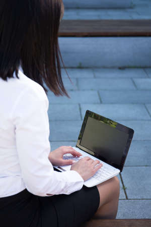 back view of business woman with laptop in city parkの写真素材