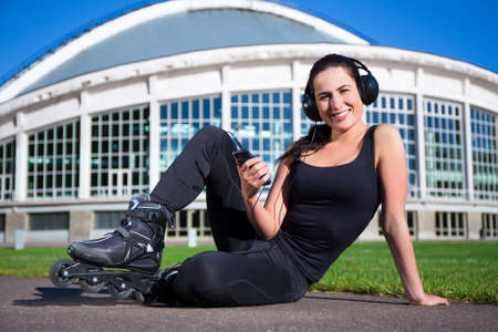 happy beautiful woman in roller skates sitting and listening musicの写真素材