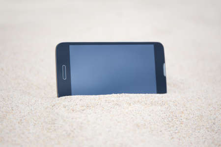 smart phone with blank screen in sand on the beachの写真素材