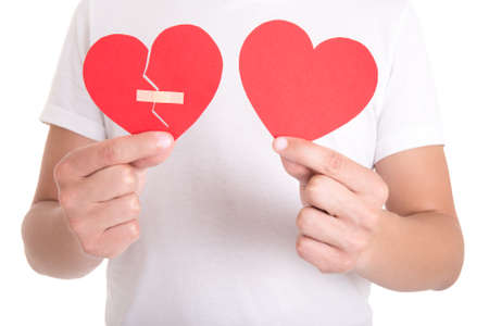 young man holding broken heart with plaster and normal paper heart