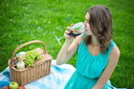 portrait of young beautiful woman drinking wine in summer parkの写真素材