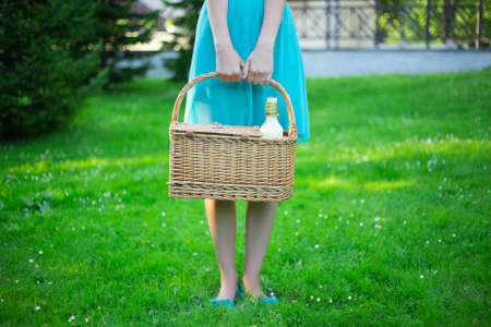 close up of picnic basket with bottle of wine in female handsの写真素材