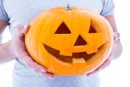 Halloween concept - close up of pumpkin Jack-O-Lantern in male hands over whiteの写真素材