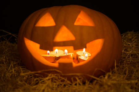 Halloween pumpkin Jack-O-Lantern Illuminated with candles over black backgroundの写真素材