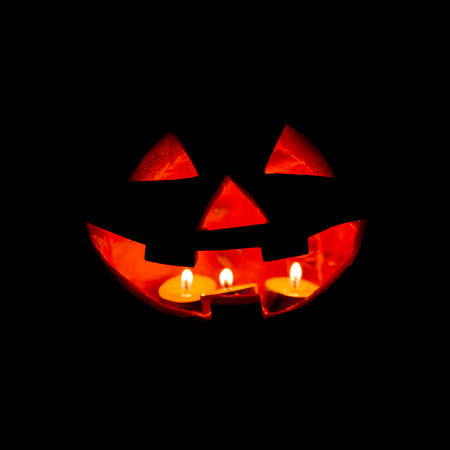 Halloween background - pumpkin Jack-O-Lantern with candles over blackの写真素材