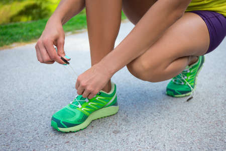 close up of woman tying shoe laces in parkの写真素材