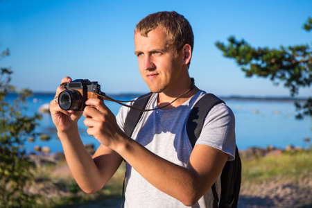 young man with backpack and camera on the beach
