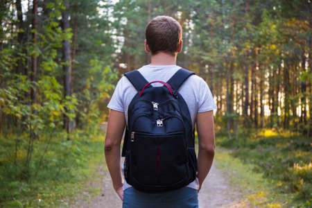 rear view of man with backpack hiking in forestの写真素材