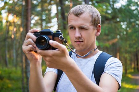 man taking a photo with retro camera in forestの写真素材