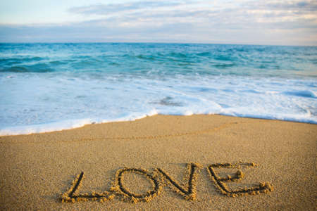 travel concept - word love written in golden sand on the beachの写真素材