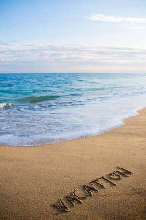 travel concept - beach background with word vacation written in sandの写真素材