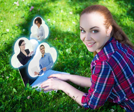 social media concept - teenage girl using laptop in park and clouds with her friendsの写真素材