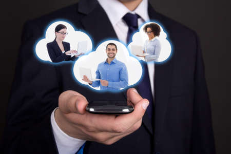 internet concept - modern smart phone in business man hand and clouds with his business partnersの写真素材
