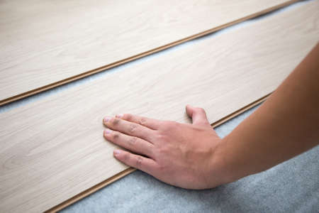 close up of male hands installing new laminated wooden floorの写真素材