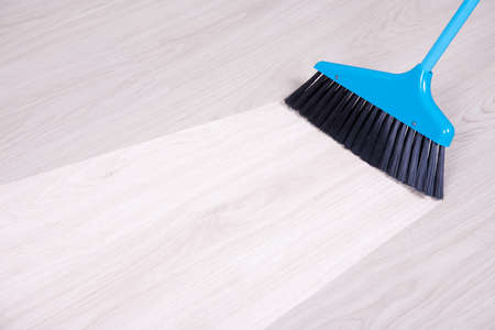 before and aftet cleaning concept - blue broom sweeping parquet floorの写真素材