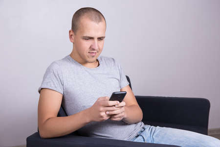 portrait of young handsome man using smart phone at homeの写真素材