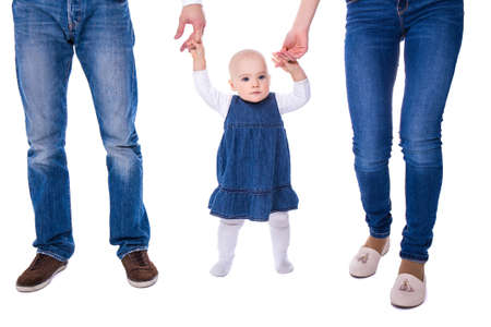 first step concept - young parents with baby girl learning to walk isolated on white background
