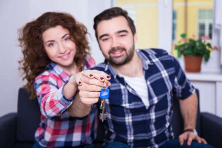 real estate concept - happy smiling young couple showing keys of their new house or flatの写真素材