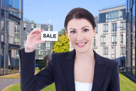 beautiful business woman real estate agent showing visiting card on street against modern office buildingの写真素材