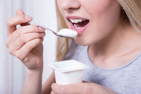 close up of woman having breakfast with yoghurt at homeの写真素材