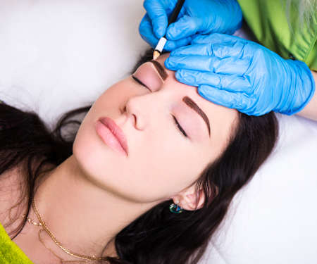 permanent eyebrow make up - close up of beautician preparing woman for procedure