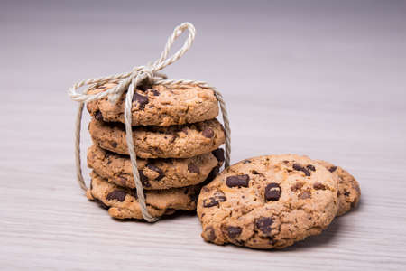 close up of freshly baked chocolate chip cookies on wooden table background
