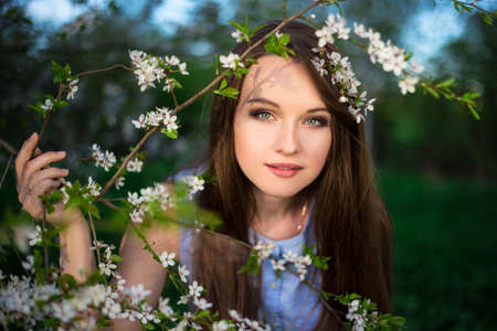 dreaming young woman with blooming cherry tree in summer garden