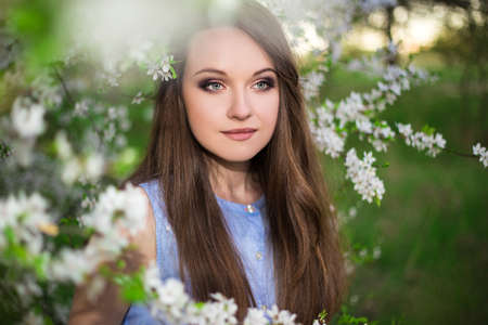 close up portrait of beautiful woman posing in blooming summer gardenの写真素材